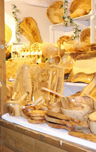 Olivenholzschüsseln, Stösel, Brettchen mit ausgeprägter Maserungiger Maserung Auslage voll mit Olivenholzprodukten
